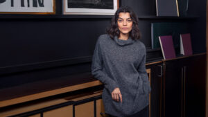 Woman in cozy sweater against dark background.