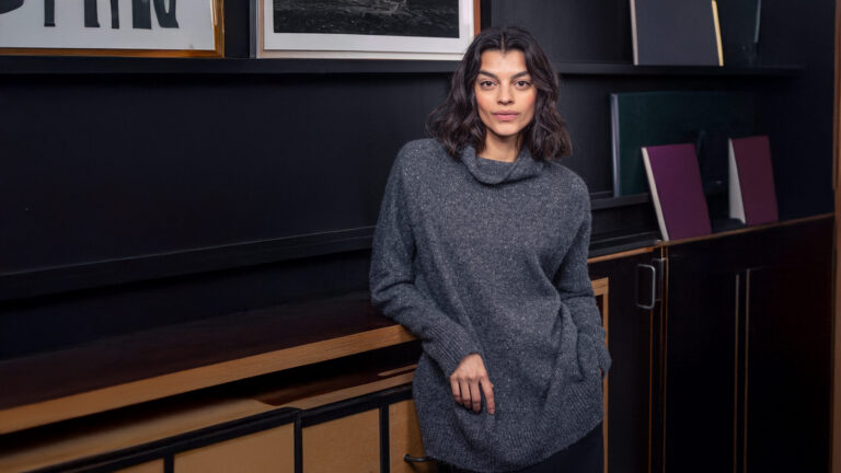 Woman in cozy sweater against dark background.