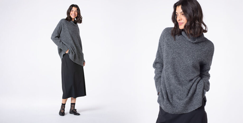 Woman smiling in a cozy gray sweater outfit.