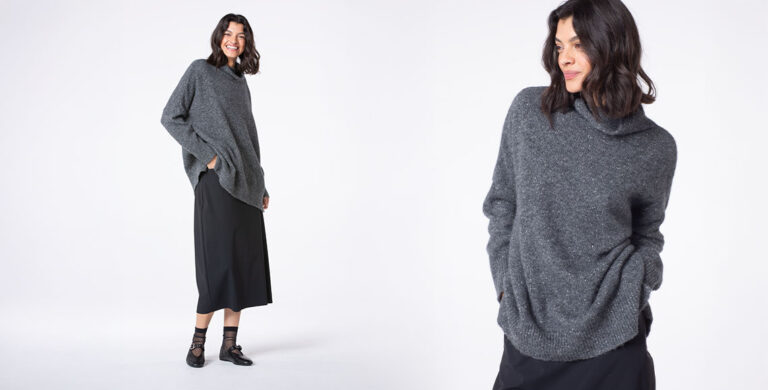Woman smiling in a cozy gray sweater outfit.