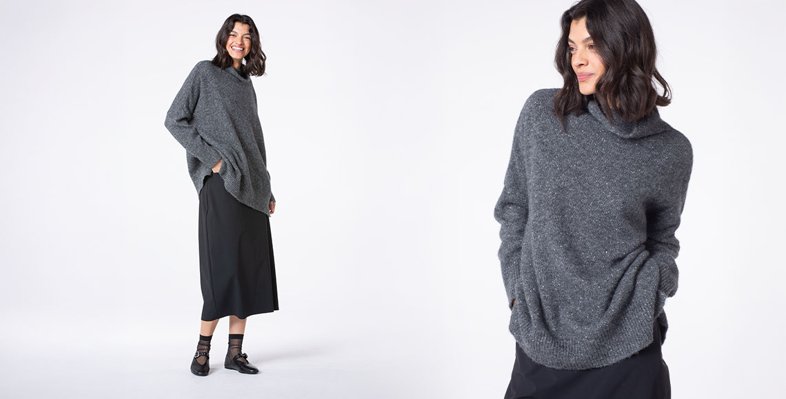 Woman smiling in a cozy gray sweater outfit.