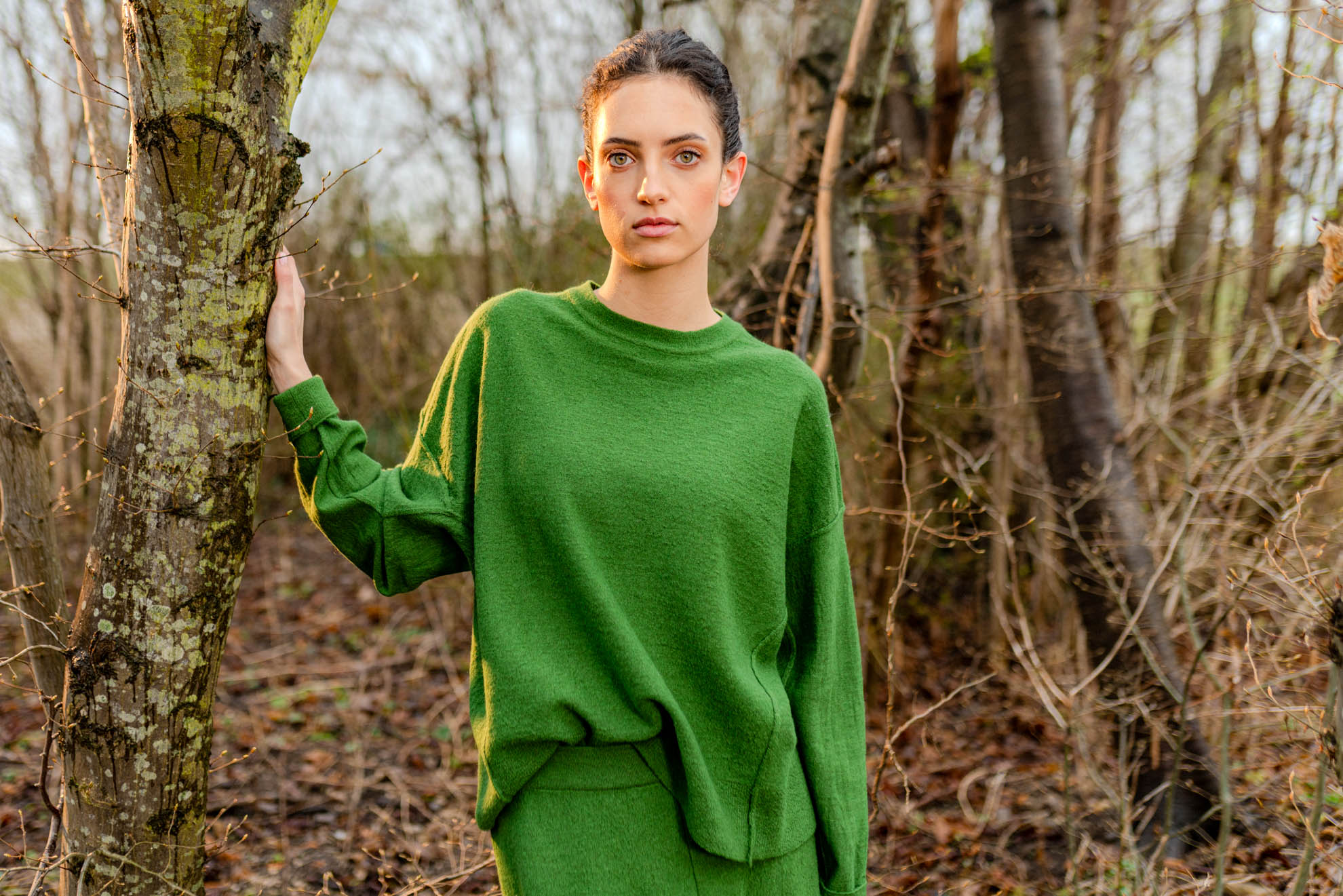 Woman in a green outfit standing between trees