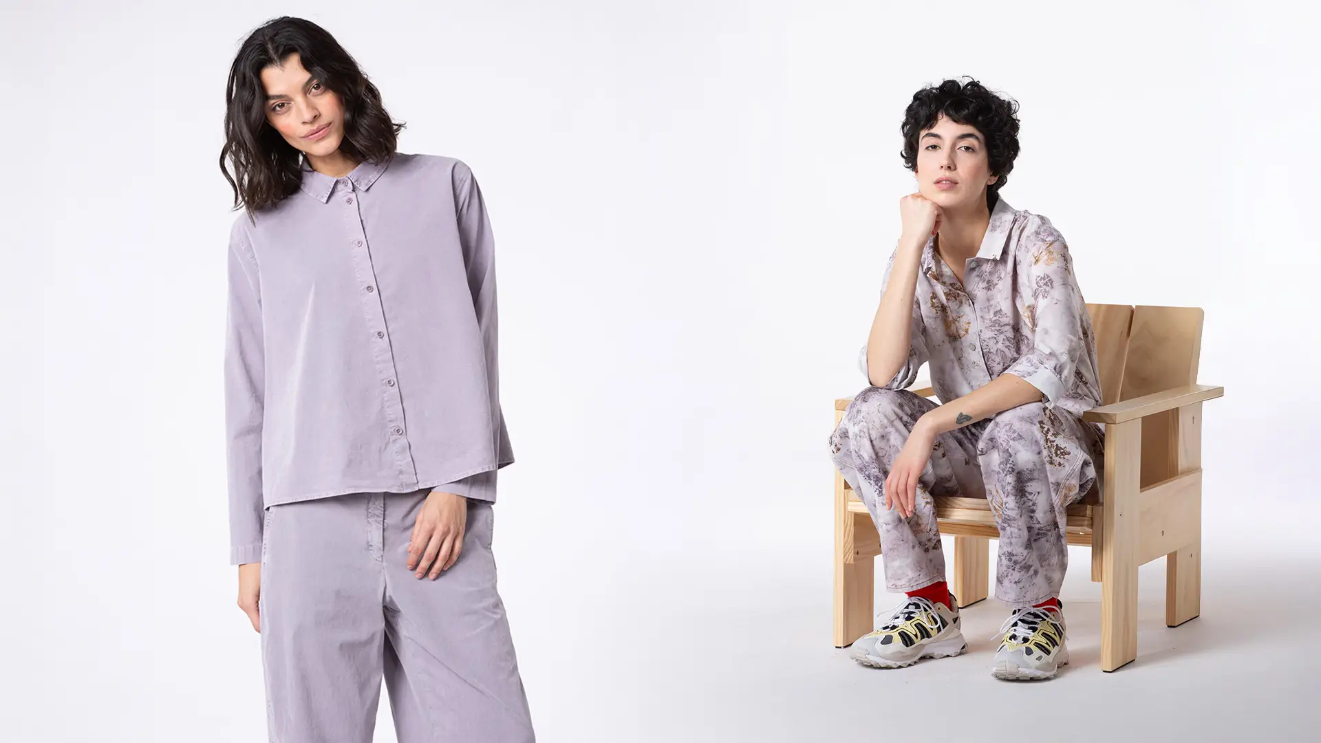 Two women modeling stylish outfits in a minimalist setting.