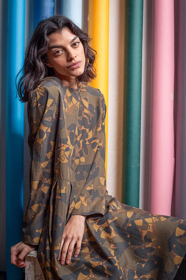 Frau in gemustertem Kleid vor farbenfrohem Hintergrund