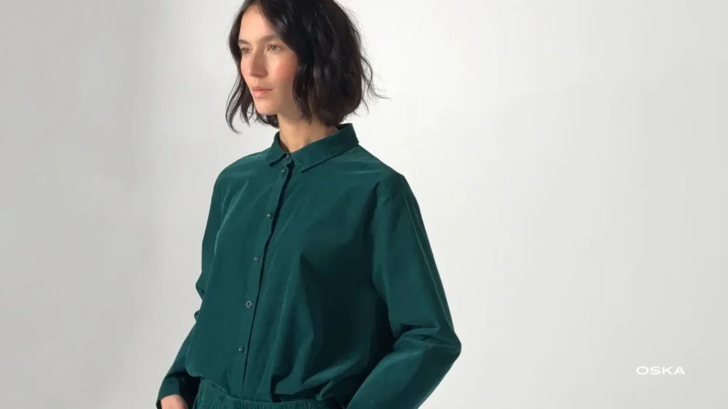 Woman wearing a teal button-up shirt.